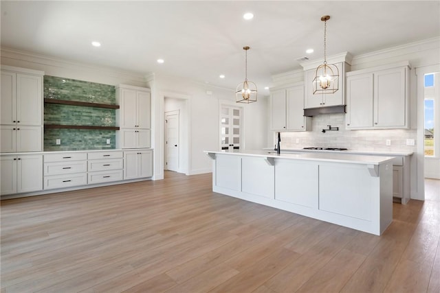 kitchen featuring a kitchen island with sink, decorative backsplash, decorative light fixtures, light hardwood / wood-style floors, and white cabinetry