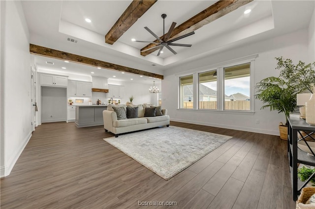 living room featuring dark hardwood / wood-style floors, beam ceiling, and ceiling fan with notable chandelier