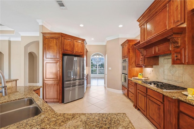 5106 Bellerive Bend Dr, College Station, TX 77845 - kitchen featuring a sink, backsplash, appliances with stainless steel finishes, light tile patterned floors, and arched walkways