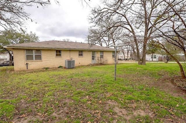 rear view of house featuring cooling unit and a lawn