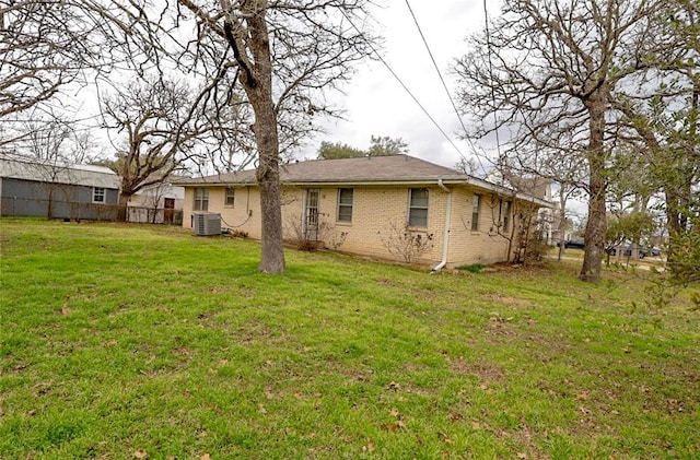 rear view of property featuring a lawn and central air condition unit