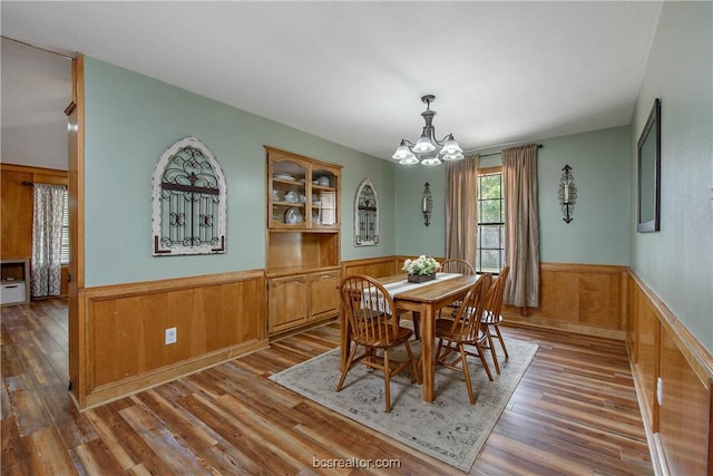 dining area featuring hardwood / wood-style floors, a notable chandelier, and wood walls