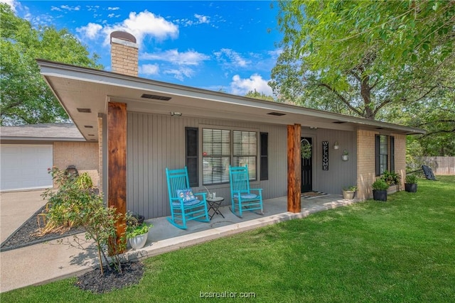 back of property with a porch, a garage, and a lawn