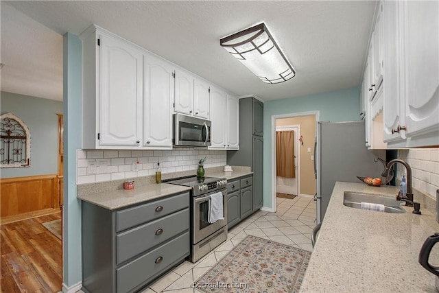 kitchen with decorative backsplash, white cabinetry, sink, and stainless steel appliances