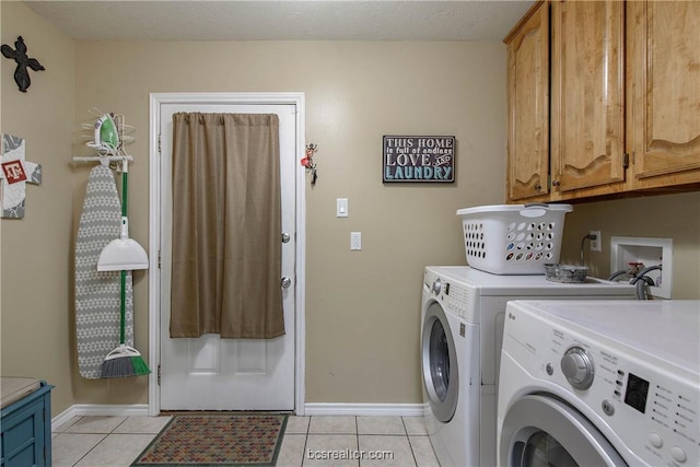 laundry room with washing machine and clothes dryer, light tile patterned floors, cabinets, and a textured ceiling