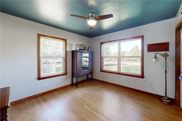 spare room with ceiling fan, a healthy amount of sunlight, and light hardwood / wood-style floors