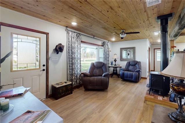 living room with wooden ceiling, plenty of natural light, a wood stove, and light hardwood / wood-style flooring