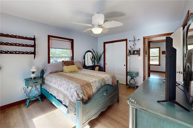 bedroom with ceiling fan, a closet, light hardwood / wood-style flooring, and multiple windows