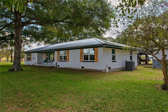 back of property featuring a lawn and central AC