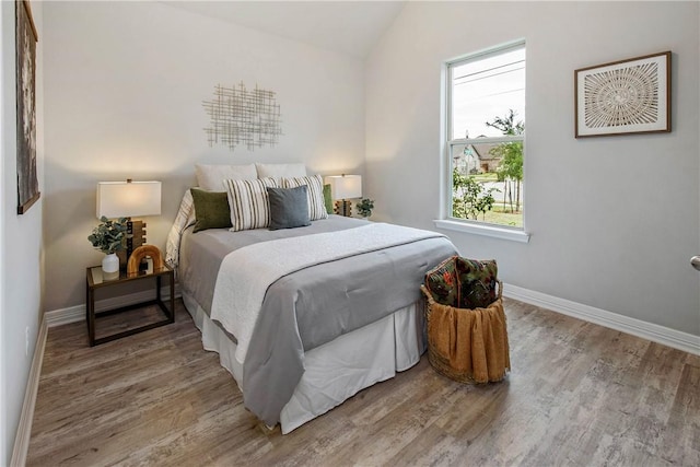 bedroom with hardwood / wood-style floors and lofted ceiling