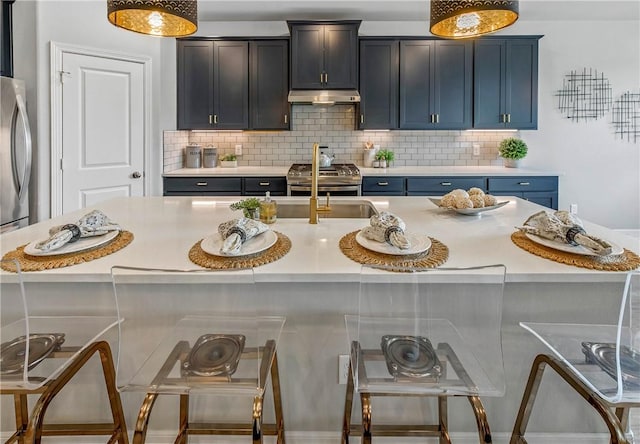 kitchen featuring backsplash, a center island with sink, blue cabinets, and stainless steel appliances