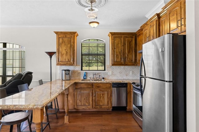 9560 County Road 121, Iola, TX 77861 - kitchen with appliances with stainless steel finishes, a peninsula, dark wood-style floors, backsplash, and brown cabinets