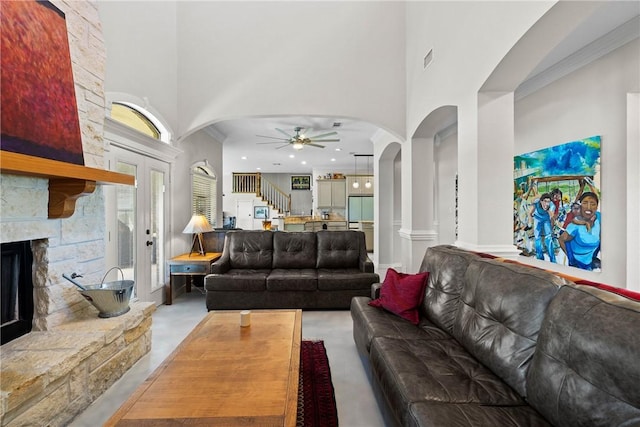 9560 County Road 121, Iola, TX 77861 - living room featuring ceiling fan, a high ceiling, a stone fireplace, stairs, and arched walkways