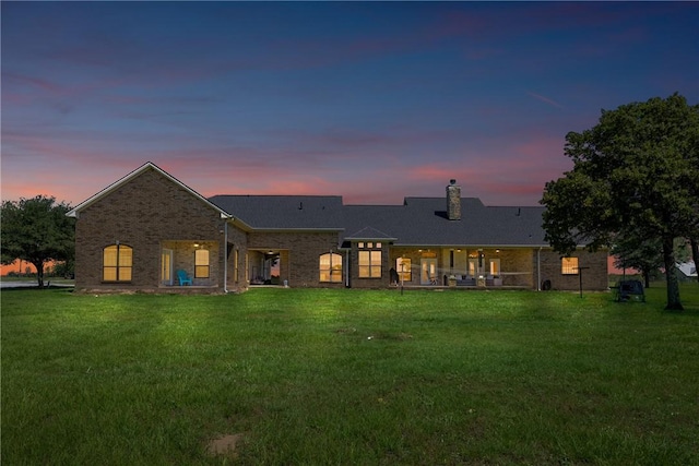 9560 County Road 121, Iola, TX 77861 - back of property at dusk with a yard, a chimney, and brick siding