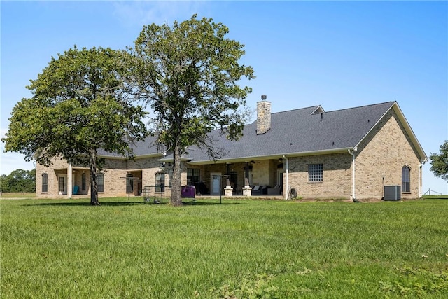 9560 County Road 121, Iola, TX 77861 - rear view of house with central AC unit, brick siding, a yard, a chimney, and a shingled roof