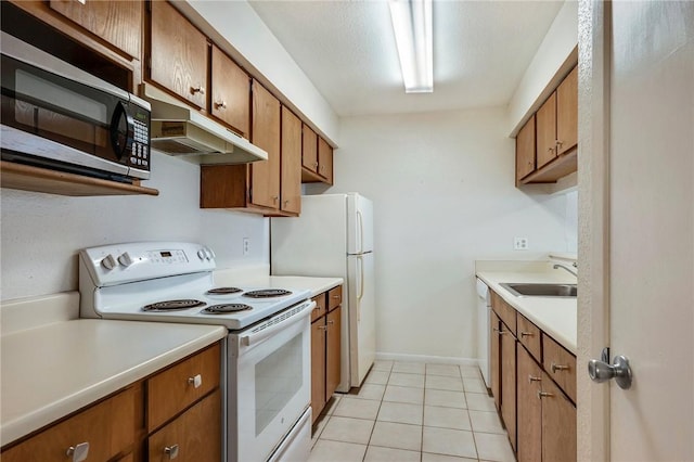 kitchen featuring under cabinet range hood, brown cabinets, white appliances, and a sink