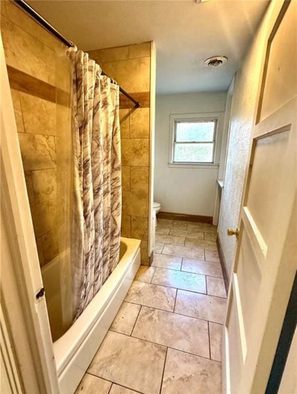 bathroom featuring tile patterned flooring, shower / bath combination with curtain, and toilet