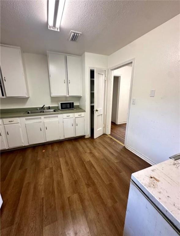 kitchen featuring dark hardwood / wood-style flooring, sink, white cabinets, and a textured ceiling