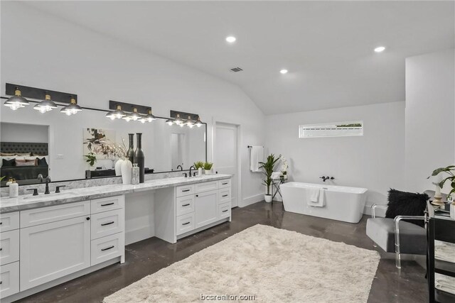 bathroom with hardwood / wood-style floors, vanity, vaulted ceiling, and a bathtub