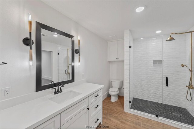 bathroom with hardwood / wood-style floors, vanity, toilet, and walk in shower