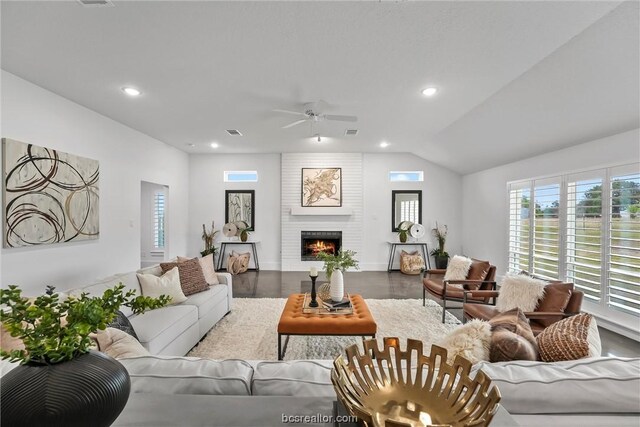 living room with hardwood / wood-style flooring, ceiling fan, a large fireplace, and vaulted ceiling