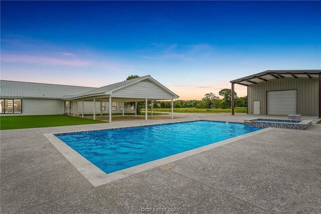 pool at dusk with an in ground hot tub and a patio