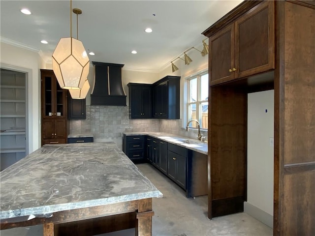 kitchen featuring light stone counters, a kitchen island, a sink, hanging light fixtures, and custom range hood