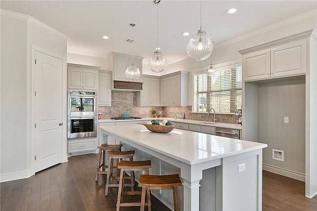 kitchen featuring dark wood-type flooring, sink, a breakfast bar area, a kitchen island, and stainless steel appliances