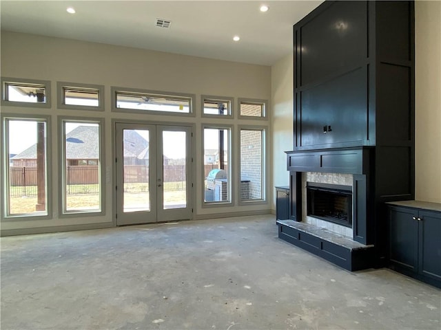 unfurnished living room featuring visible vents, concrete flooring, french doors, a fireplace, and recessed lighting