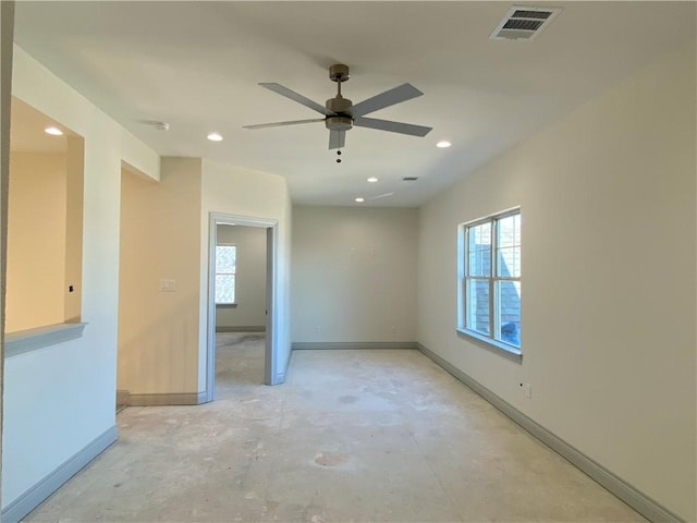 spare room featuring a healthy amount of sunlight, baseboards, visible vents, and unfinished concrete flooring