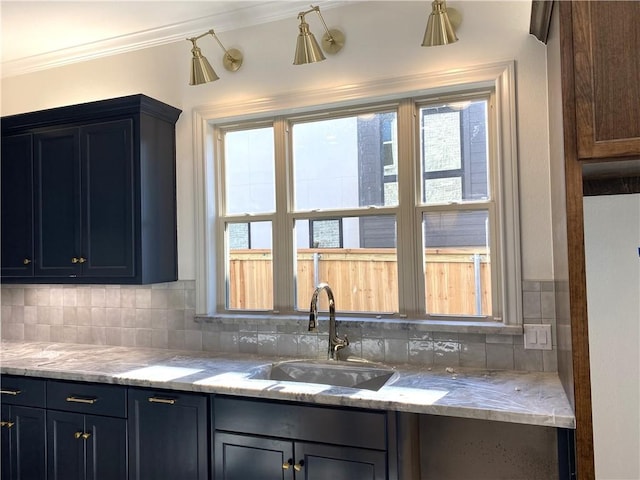 kitchen featuring tasteful backsplash, crown molding, a sink, and light stone counters