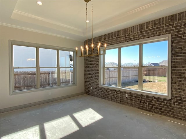 spare room featuring brick wall, a tray ceiling, concrete floors, and a wealth of natural light