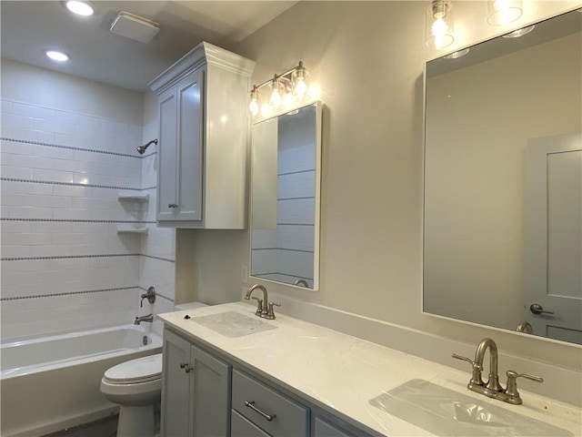 bathroom featuring double vanity, bathtub / shower combination, a sink, and toilet