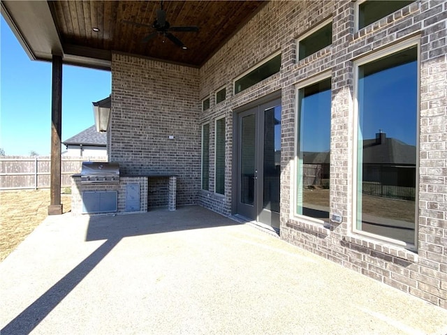 view of patio featuring a ceiling fan, fence, grilling area, and exterior kitchen