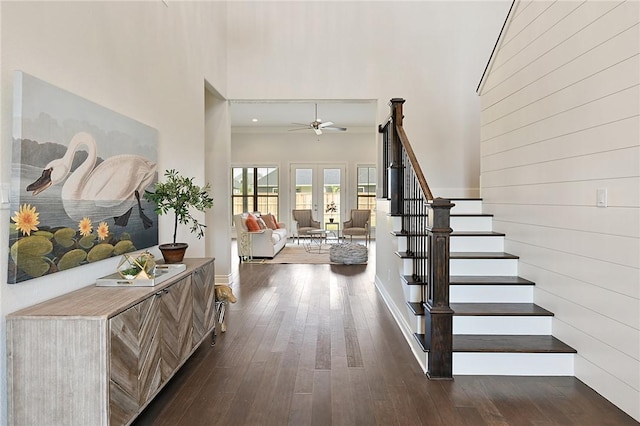 entrance foyer featuring french doors, wooden walls, ceiling fan, dark hardwood / wood-style floors, and a towering ceiling