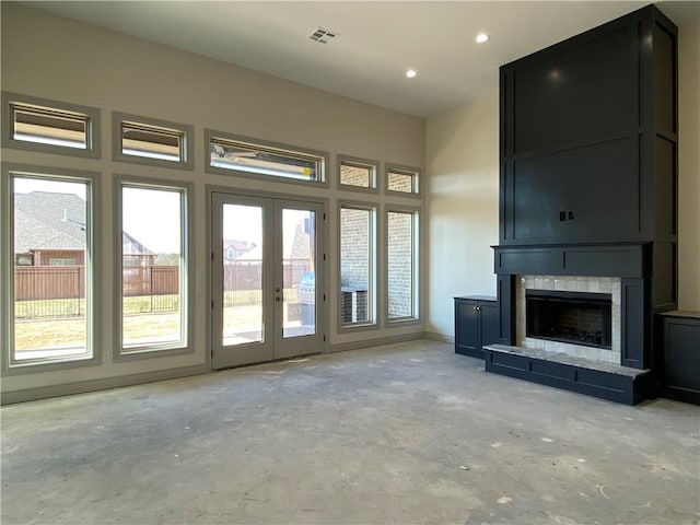 unfurnished living room featuring french doors, a fireplace, visible vents, and unfinished concrete flooring