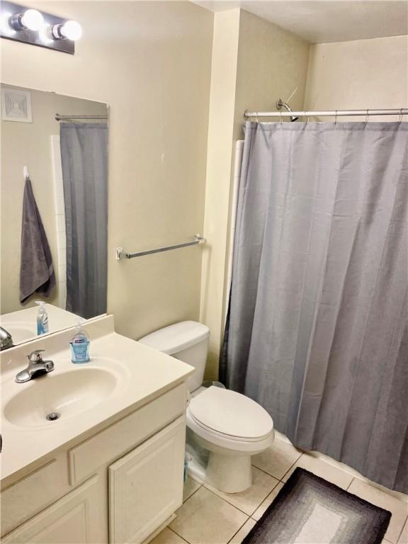 bathroom featuring tile patterned flooring, vanity, curtained shower, and toilet