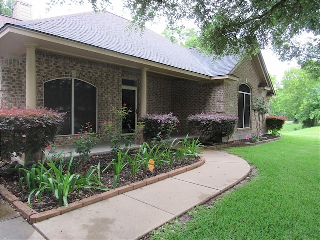 2400 Brookbend Dr, Brenham, TX 77833 - rear view of property featuring brick siding, a lawn, a chimney, and roof with shingles
