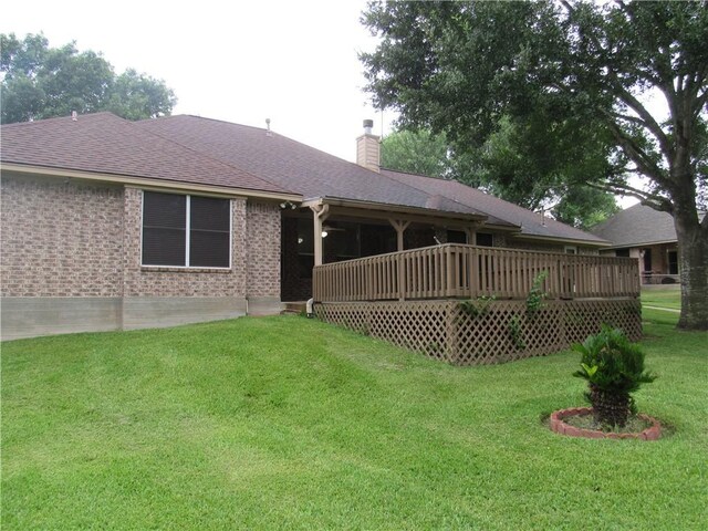 2400 Brookbend Dr, Brenham, TX 77833 - back of property featuring a yard, a chimney, a shingled roof, a wooden deck, and brick siding