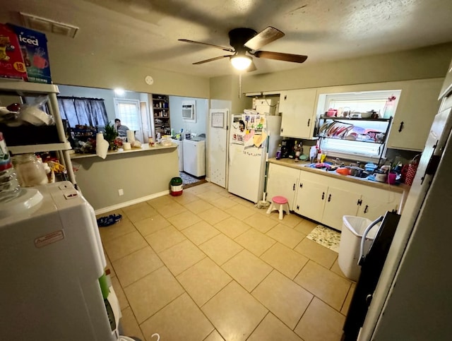 kitchen featuring washer and dryer, ceiling fan, white cabinetry, and white fridge