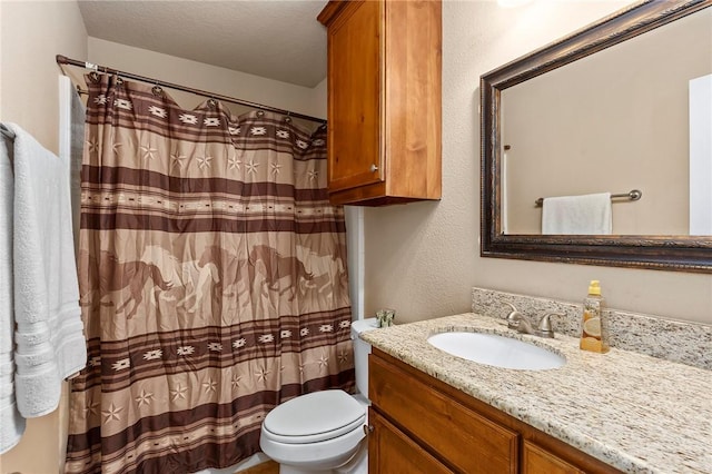 bathroom with vanity, toilet, and a textured ceiling