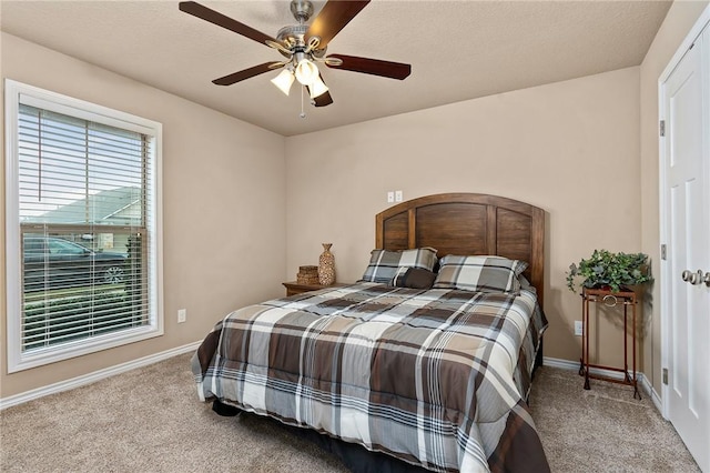 carpeted bedroom featuring ceiling fan and a textured ceiling