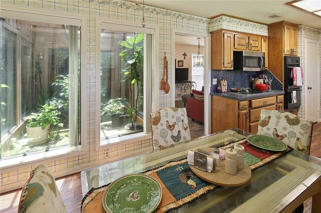 2801 Celinda Cir, College Station, TX 77845 - kitchen with stainless steel microwave, brown cabinetry, stovetop, and dark countertops