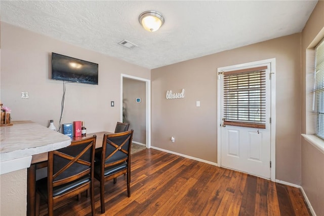 dining space with visible vents, a textured ceiling, baseboards, and hardwood / wood-style floors