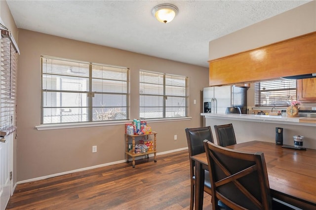 dining space with a textured ceiling, baseboards, and wood finished floors