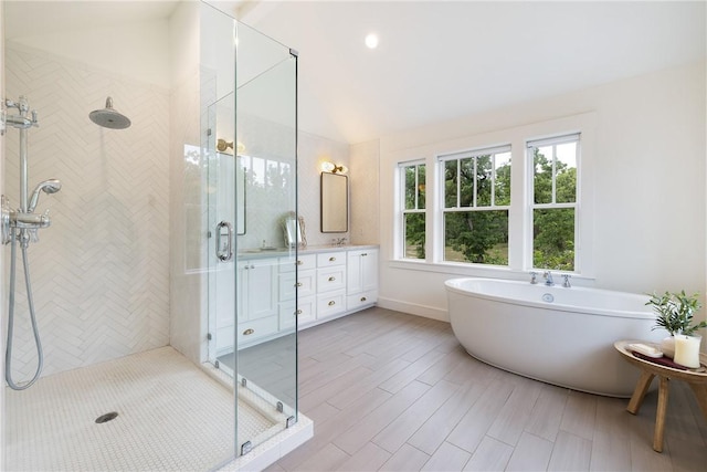 full bath featuring a freestanding bath, vanity, a shower stall, and vaulted ceiling