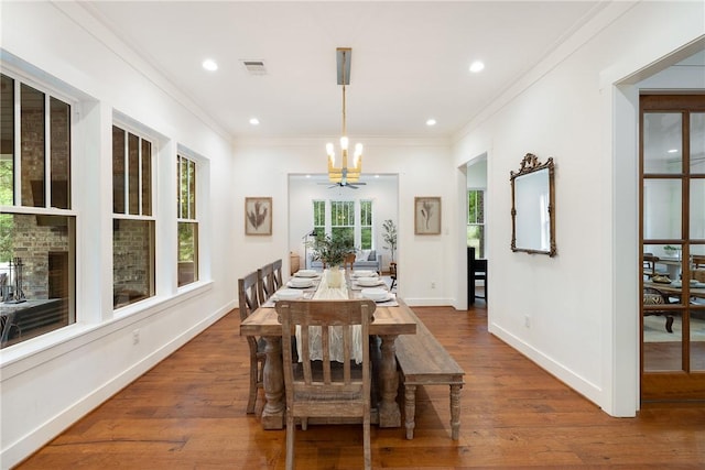 dining room featuring a chandelier, ornamental molding, wood finished floors, and visible vents