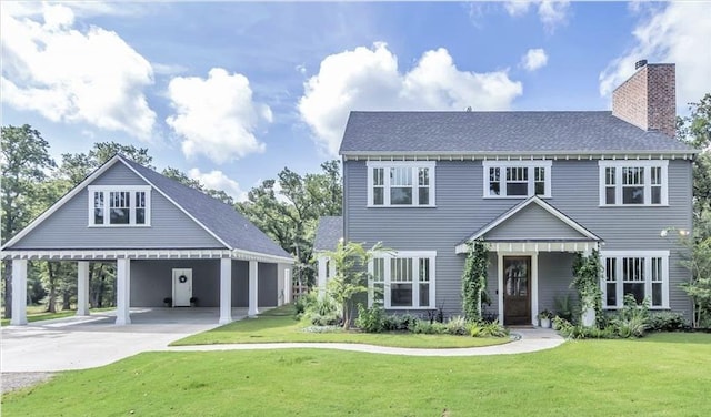 colonial inspired home featuring concrete driveway, a chimney, a front yard, and an attached carport