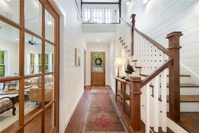 foyer entrance featuring crown molding, wood finished floors, wooden walls, stairway, and a ceiling fan