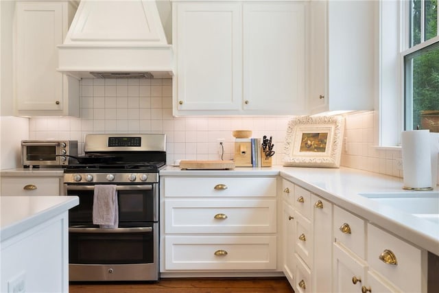 kitchen with light countertops, white cabinetry, double oven range, and custom range hood